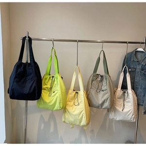 Detail showing various colors of drawstring tote bags on a display rack with nylon texture