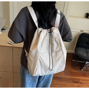 Rear view of a model wearing the large capacity drawstring backpack in off-white fabric