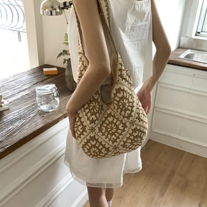 Detail of woven floral hobo bag worn by model, showing boho style and texture