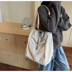 Detail of a large cream drawstring shoulder bag styled for daily student life