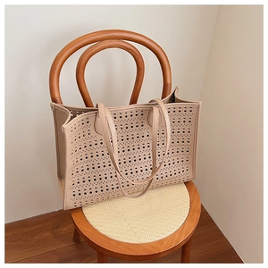 Détail d'un sac cabas beige ajouré avec des motifs circulaires découpés au laser