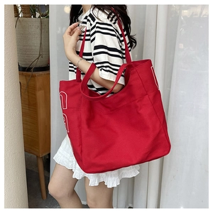 Close-up of red canvas tote bag with wide shoulder strap and spacious interior