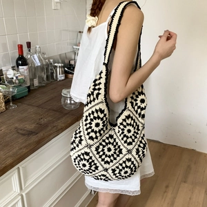 Close-up of a handmade black and white crochet pattern on a large woven tote bag