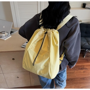 Detail view of water-resistant light yellow drawstring backpack with front pocket and black lock