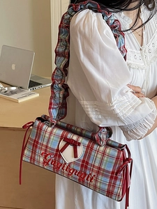 Fashionable plaid shoulder bag with red ruffle strap and heart detail shown on a model