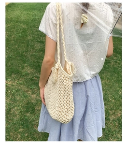 Close-up of beige woven tote bag with hollow mesh design and fringe tassel details