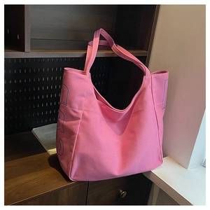 Detail view of pink canvas tote bag with bold blue letter printing and thick texture