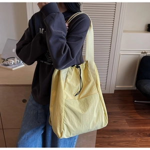 Detail of yellow nylon drawstring backpack with large front pocket and wide strap