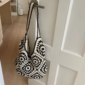 Detail of hand-woven crochet tote bag featuring black and white floral patterns