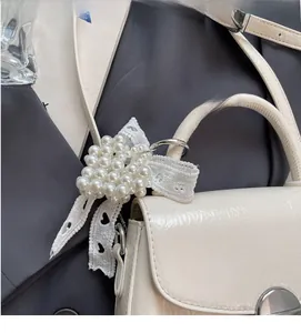 Détail d'un bijou de sac en perles en forme de cœur avec ruban en dentelle sur un sac