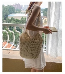 Detail of hollow woven tote bag featuring fringe accents and creamy beige knit texture