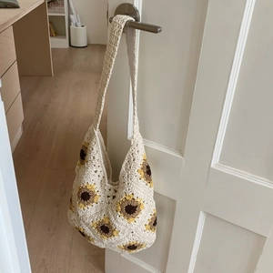 Close-up of handmade crochet sunflower tote bag hanging on a white wooden door handle