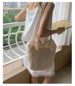 Close-up of cream woven tote bag featuring hollow texture and stylish fringe tassels