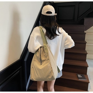 Close-up of beige drawstring backpack showing nylon texture and wide shoulder strap detail