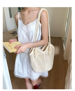 Detail of hand-woven cream tote bag showing mesh pattern and decorative side tassels