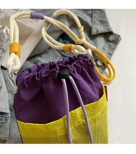 Detail view of nylon bucket bag with color-block purple body and yellow plaid pocket