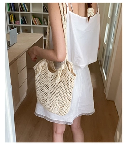 Detail view of beige hand-woven shoulder bag showing mesh texture and long tassels