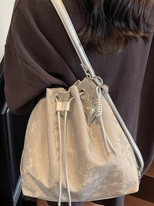 Minimalist silver drawstring bucket bag with heart pendant and textured fabric finish