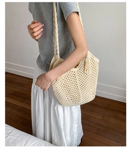 Close-up of beige crochet shoulder bag with hollow mesh pattern and tassels on model
