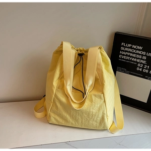 Close-up of lightweight yellow nylon drawstring bag with textured fabric and wide straps