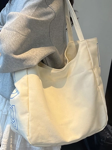 Large cream canvas tote bag with blue geometric lettering for students and commuting