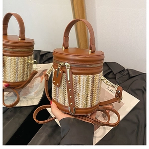Close-up of woven bucket bag featuring brown leather handle and zipper detail