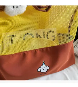 Detail of yellow mesh and brown fabric tote bag with a cute dog print and plush charm