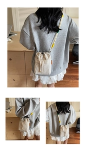 Detail of canvas bucket bag with color-block rope strap and orange brand label accents