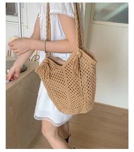 Detailed close-up of large woven tote bag with openwork mesh and long side tassels