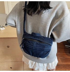 Gros plan d'un sac bandoulière en denim bleu foncé avec double fermeture éclair au bureau