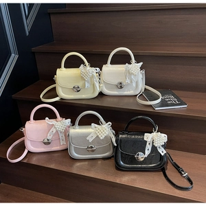 Détail de mini sacs bandoulière en cinq couleurs avec breloques cœur perle et cuir brillant