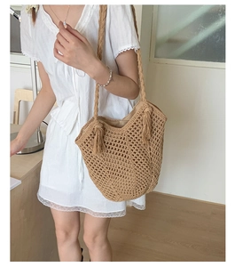 Detail of khaki woven tote bag showing hollow-out texture and stylish side tassels