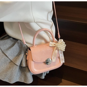 Détail du sac bandoulière rose plissé avec breloque cœur perlée et boucle argentée