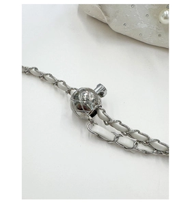 Detailed view of silver chain strap with quilted adjustable ball buckle and white leather