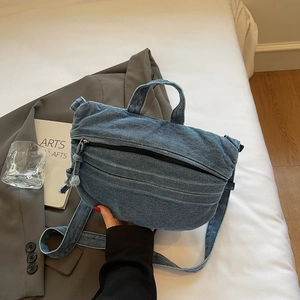 Détail du sac cabas en jean bleu montrant la fermeture éclair et la bandoulière