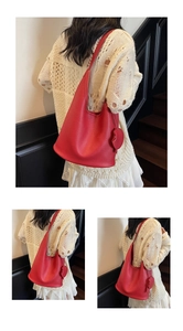 Detail view of red lychee grain leather shoulder bag with a heart-shaped charm accessory