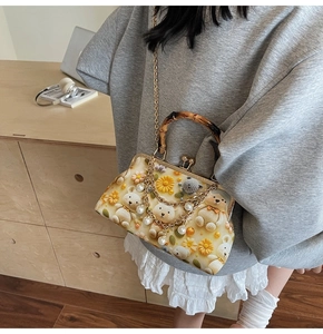 Detail view of retro floral handbag featuring bamboo handle and pearl metal chain