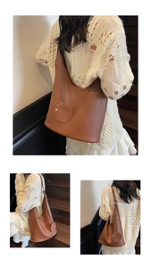 Detail of caramel leather hobo bag featuring a round decorative coin purse on the side
