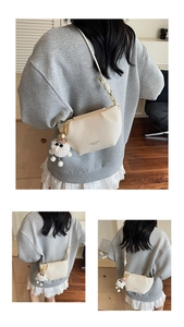 Detail of cream-white leather cloud bag with plush pendant and zip closure