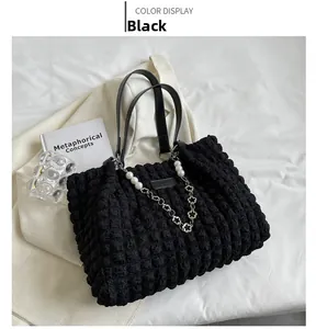 Detail of black popcorn texture tote bag with elegant pearl and floral metal chain straps