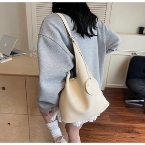Detail of cream-white bucket shoulder bag featuring pebble grain leather texture