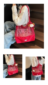 Detail of red mesh tote bag with cartoon print and white plush charm on a shoulder strap