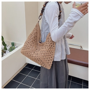 Detail of hollow woven straw tote bag featuring vintage dark wooden bead shoulder straps