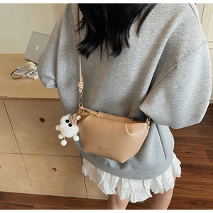 Detail of khaki crossbody bag with plush charm and MAILETAO logo on a wooden desk