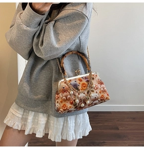Detail of vintage frame bag featuring bamboo handle, knit bear, and pearl chain strap