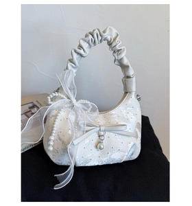 Detail of white lace hobo bag with pearl charms, silk bow and pleated leather handle