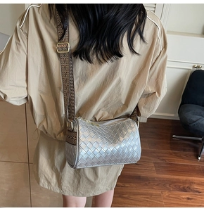 Detailed macro of silver woven pillow bag with chic patterned fabric strap and gold hardware
