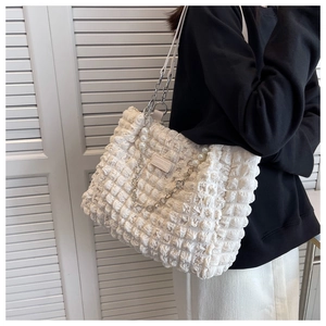 Detail of white bubble quilted tote bag with silver chain and pearl flower charm