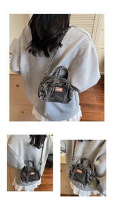 Detail showing vintage black washed denim texture and brown leather patch on mini handbag
