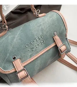 Detailed close-up of washed denim boston bag with embossed logo and contrast PU leather trim